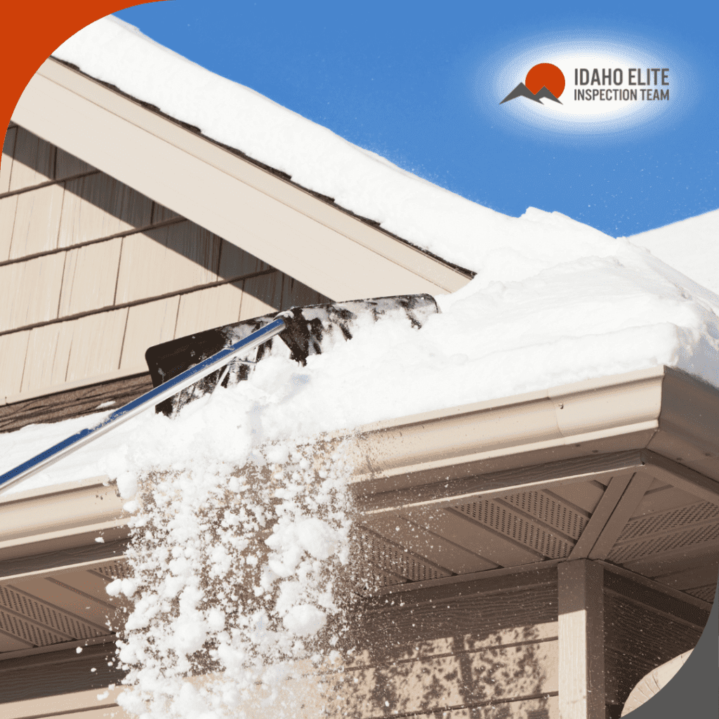 Snow being removed from a house roof with a roof rake under a clear blue sky.