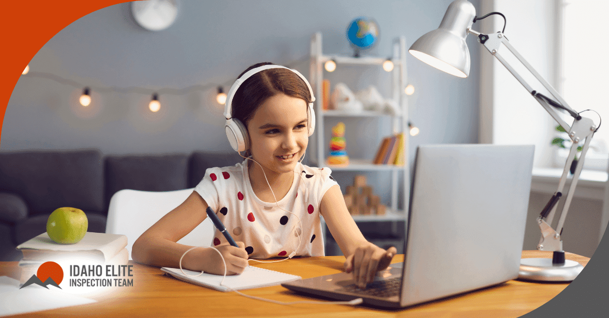 Smiling girl with headphones studying on a laptop at a well-lit desk.
