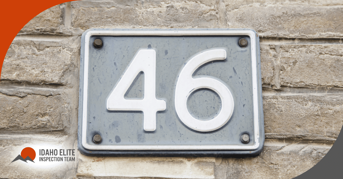 White house number 46 on a gray plaque attached to a brick wall