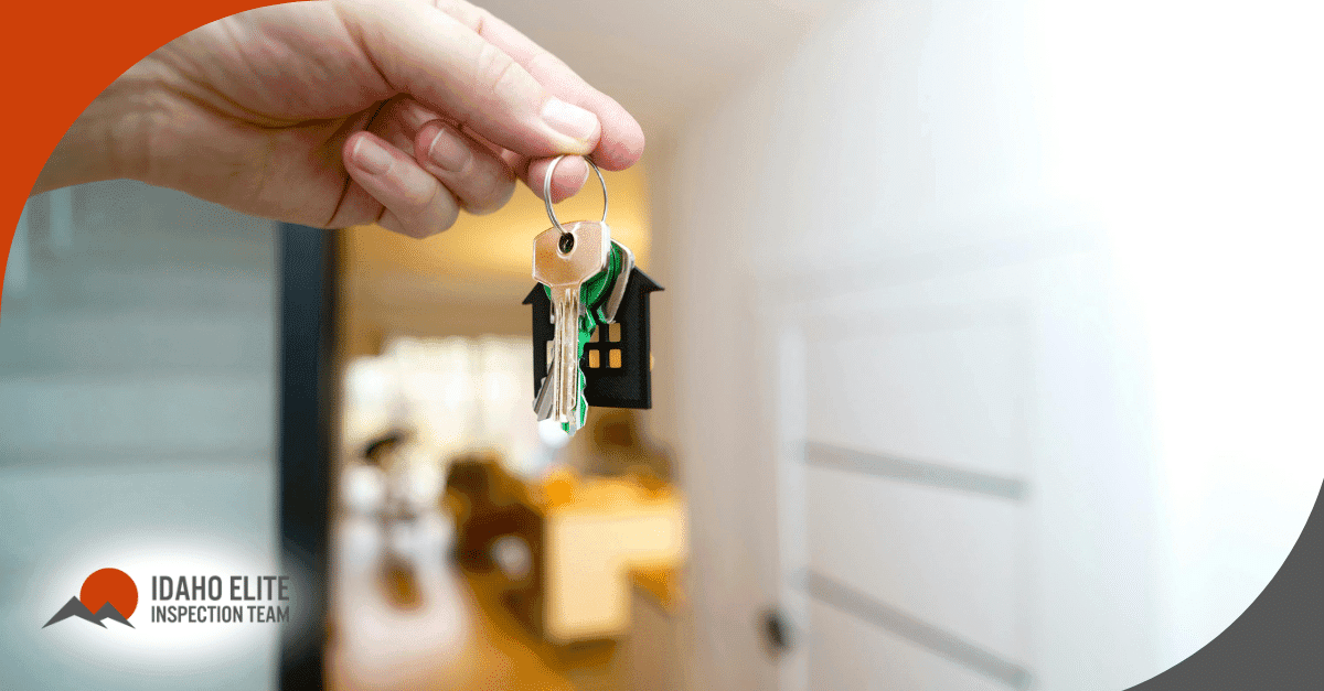 Hand holding house keys near a front door.