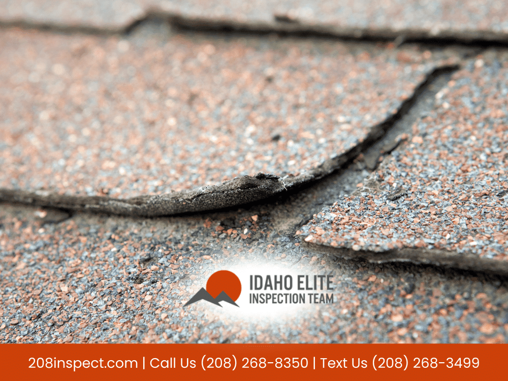 Here is an SEO-optimized alt text under 125 characters: Damaged asphalt roof shingles lifting after heavy snow and wind in Idaho Falls home