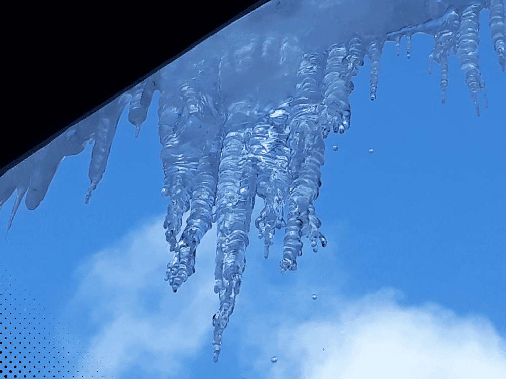 Icicles hanging from a roof on a clear day.