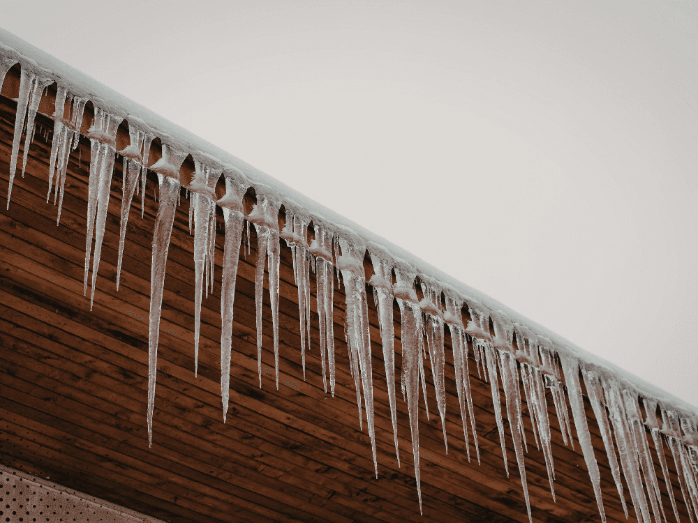 Long icicles hanging from roof edge indicating ice dam buildup in Idaho Falls winter conditions